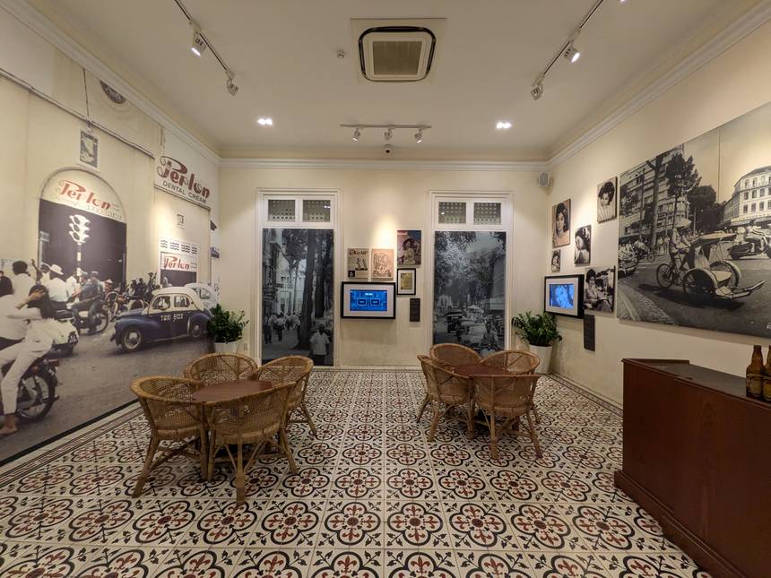 統一会堂の展示館の部屋。籐の椅子とテーブルが置かれ、壁に昔のサイゴンの街の大きな写真が貼られている