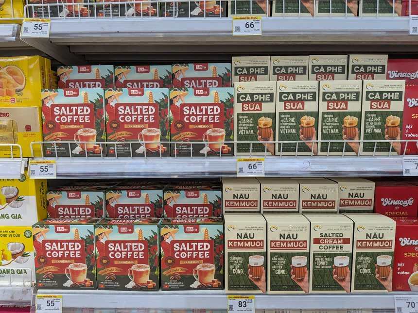 スーパーの棚のコンカフェのインスタント「NÂU KEM MUỐI／SALTED CREAM COFFEE」のベージュの箱。値札は83,000ドン。