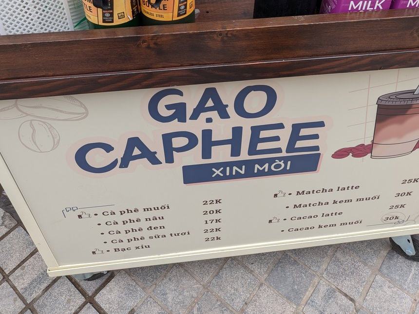 路上の屋台「GẠO CAPHEE」のメニュー。Cà phê muối 22K、Cà phê nâu 20K、Matcha kem muối 30Kなどが並ぶ。