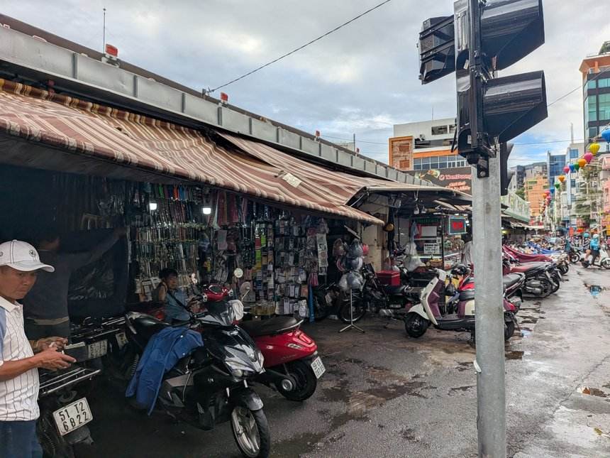 タンディン市場の外の通り。ひさしの下に小物の店が並び、バイクが停まっている