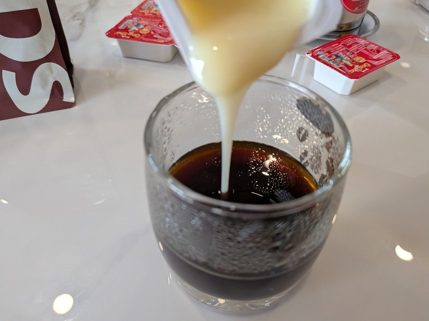 淹れたコーヒーに、Ông Thọのカップから練乳を注いでいるところ