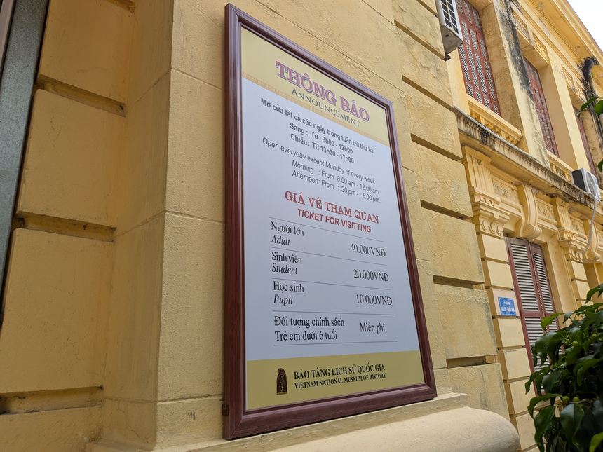 ベトナム国立歴史博物館の2号館の壁に掛かる掲示。月曜以外の開館時間と、大人40,000ドンなどの入場料が書かれている