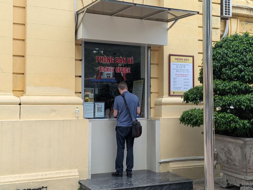 ベトナム国立歴史博物館の2号館の券売所。PHÒNG BÁN VÉ/TICKET OFFICEと書かれた窓口で、旅行者がチケットを買っている