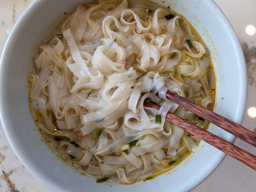 Cung Đình Phở Gà Hà Nộiを作った丼。平たい米の麺が澄んだスープに入っている。