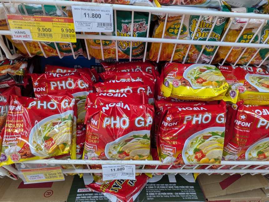 スーパーのフォー売り場。赤いVIFONのPhở Gàが積まれ、11,800ドンの値札が付いている。