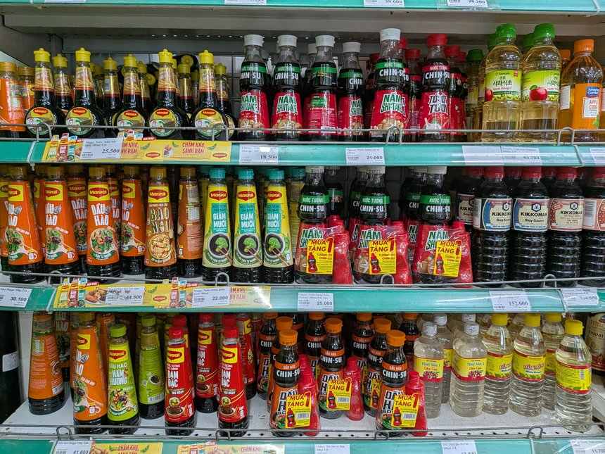スーパーの醤油とソースの棚。MaggiやChin-su、Kikkomanのボトルが3段に並ぶ