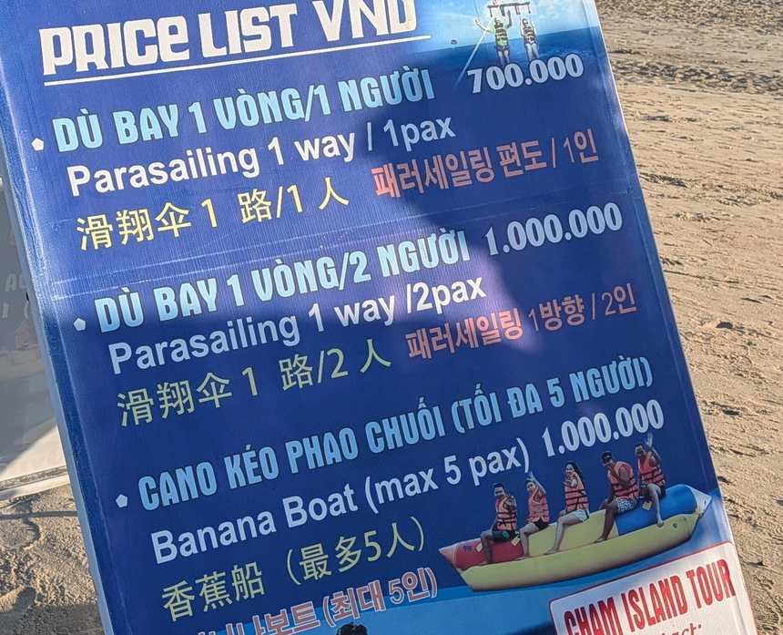 浜に立っていたマリンスポーツの料金表。パラセーリング1人700,000ドン、2人1,000,000ドン、バナナボート（5人まで）1,000,000ドンと出ている