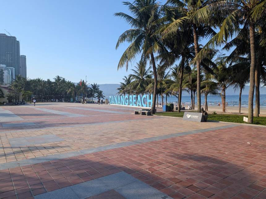 浜沿いの広場に立つ「DANANG BEACH」の青い大きな文字と、ヤシの木の並ぶ海辺