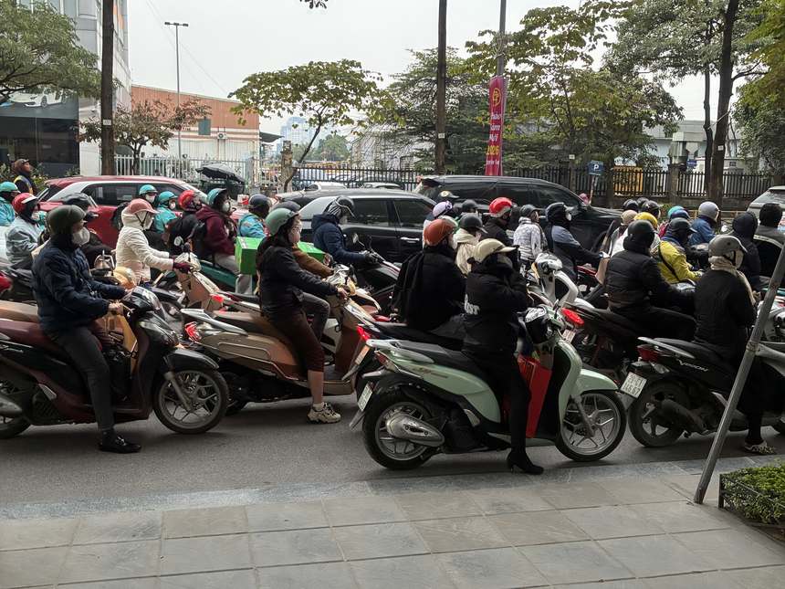2026年1月23日夕方のハノイの通り。信号待ちのバイクの列で、ダウンや厚手の上着を着た人が多い