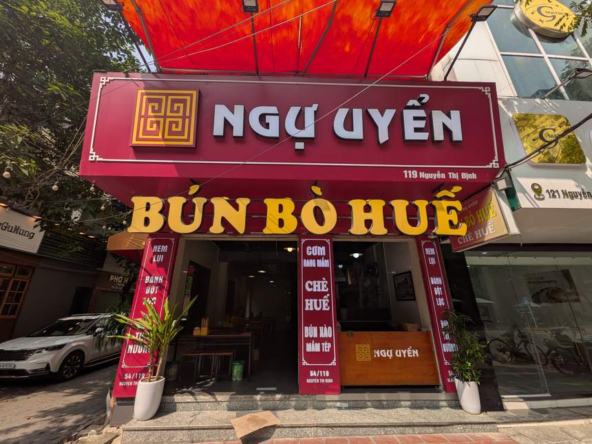 ハノイのブンボーフエの店「NGỰ UYỂN」の外観。赤い看板に「119 Nguyễn Thị Định」、その下に黄色い大きな文字で「BÚN BÒ HUẾ」とある