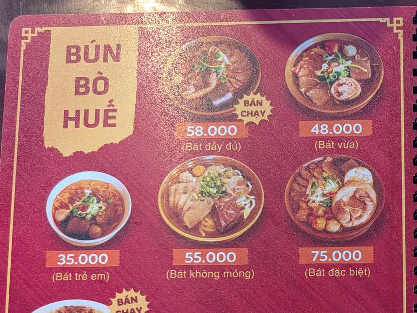 ハノイのブンボーフエの店のメニュー。「BÚN BÒ HUẾ」の欄に、58.000(Bát đầy đủ)、48.000(Bát vừa)、35.000(Bát trẻ em)、55.000(Bát không móng)、75.000(Bát đặc biệt)の5つの値段が並ぶ