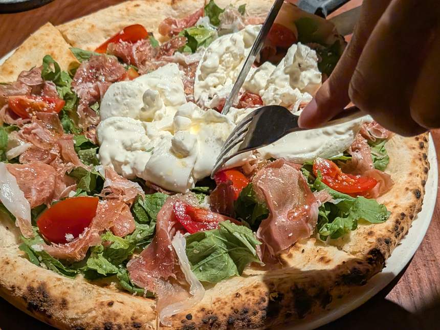 Pizza 4P'sのブッラータ・パルマハムのピザ。フォークで割ったブッラータの中のやわらかいチーズ